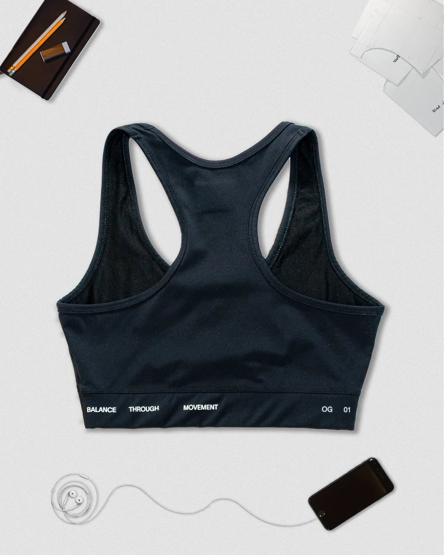 OG 01 women’s performance top back flatlay — racerback design showing Balance Through Movement slogan
