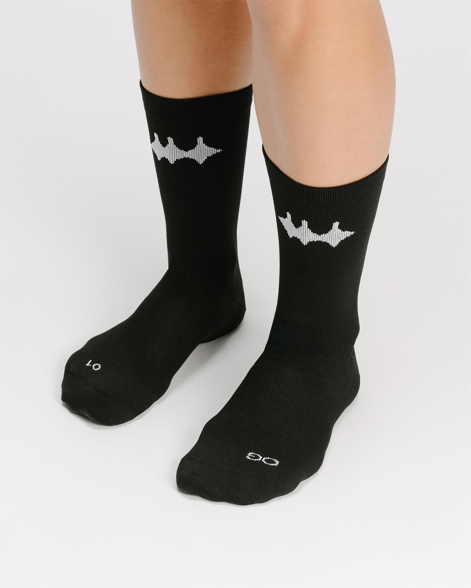 OG 01 black socks worn front on model — black crew socks with white logo visible on front