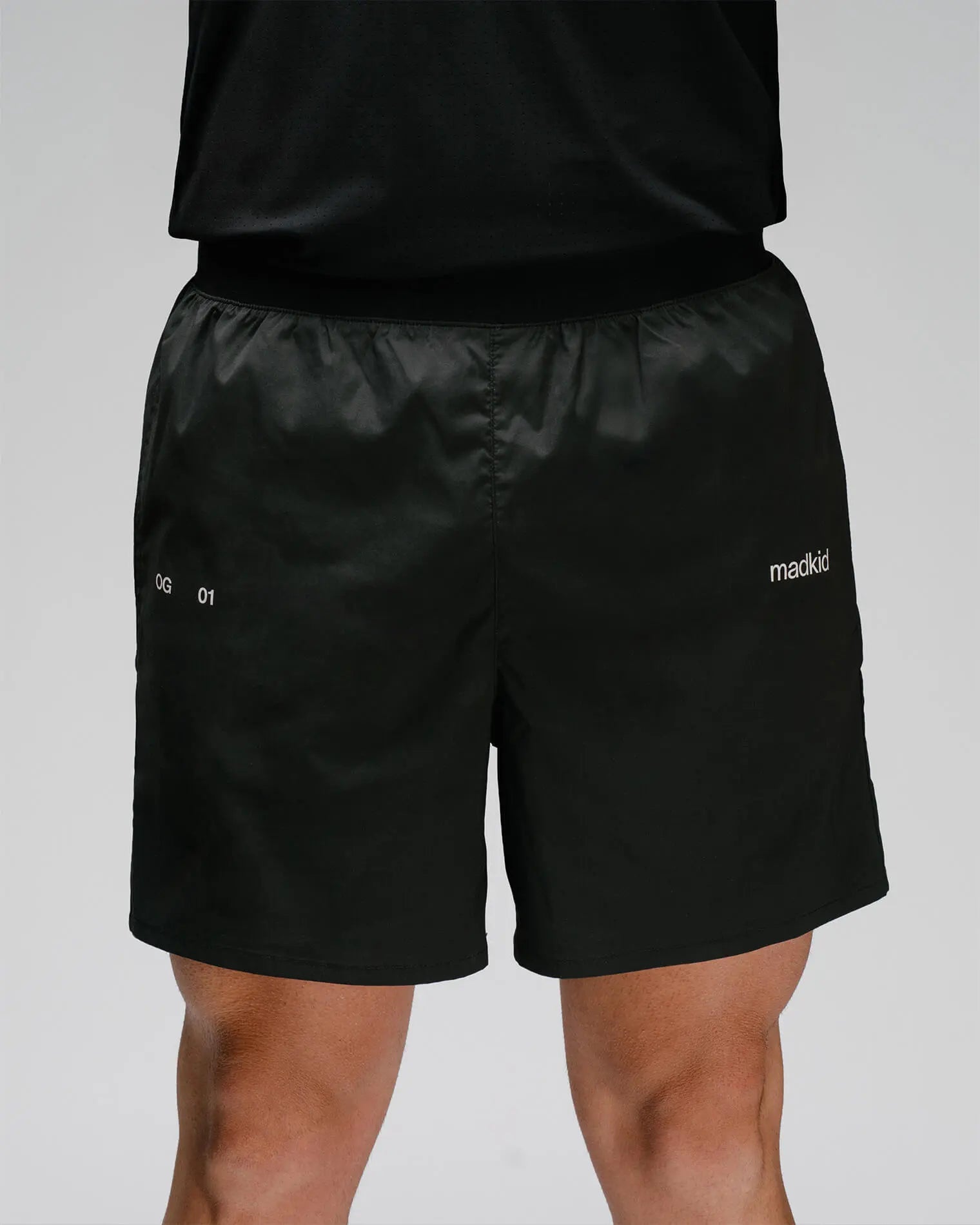 OG 01 men’s shorts front view — lightweight black technical shorts with logo print and elastic waistband by Madkid