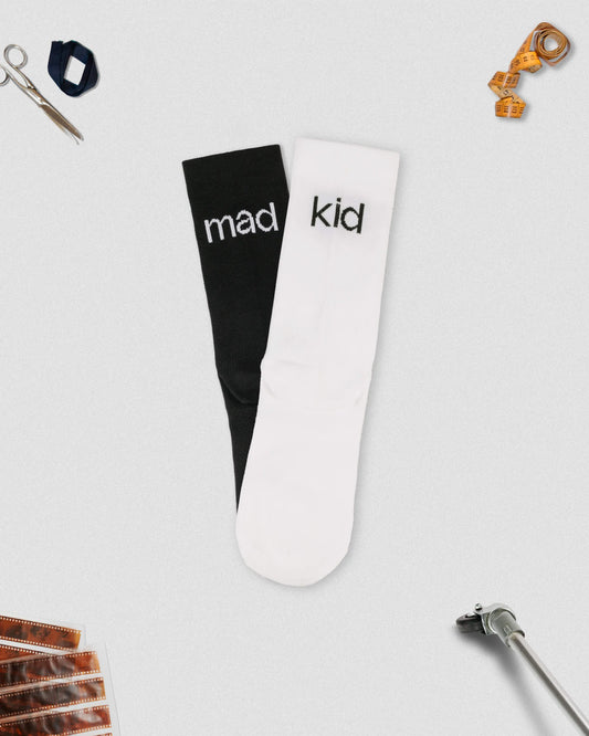 OG 01 mixed socks back flatlay with props — contrasting black and white socks showing madkid lettering