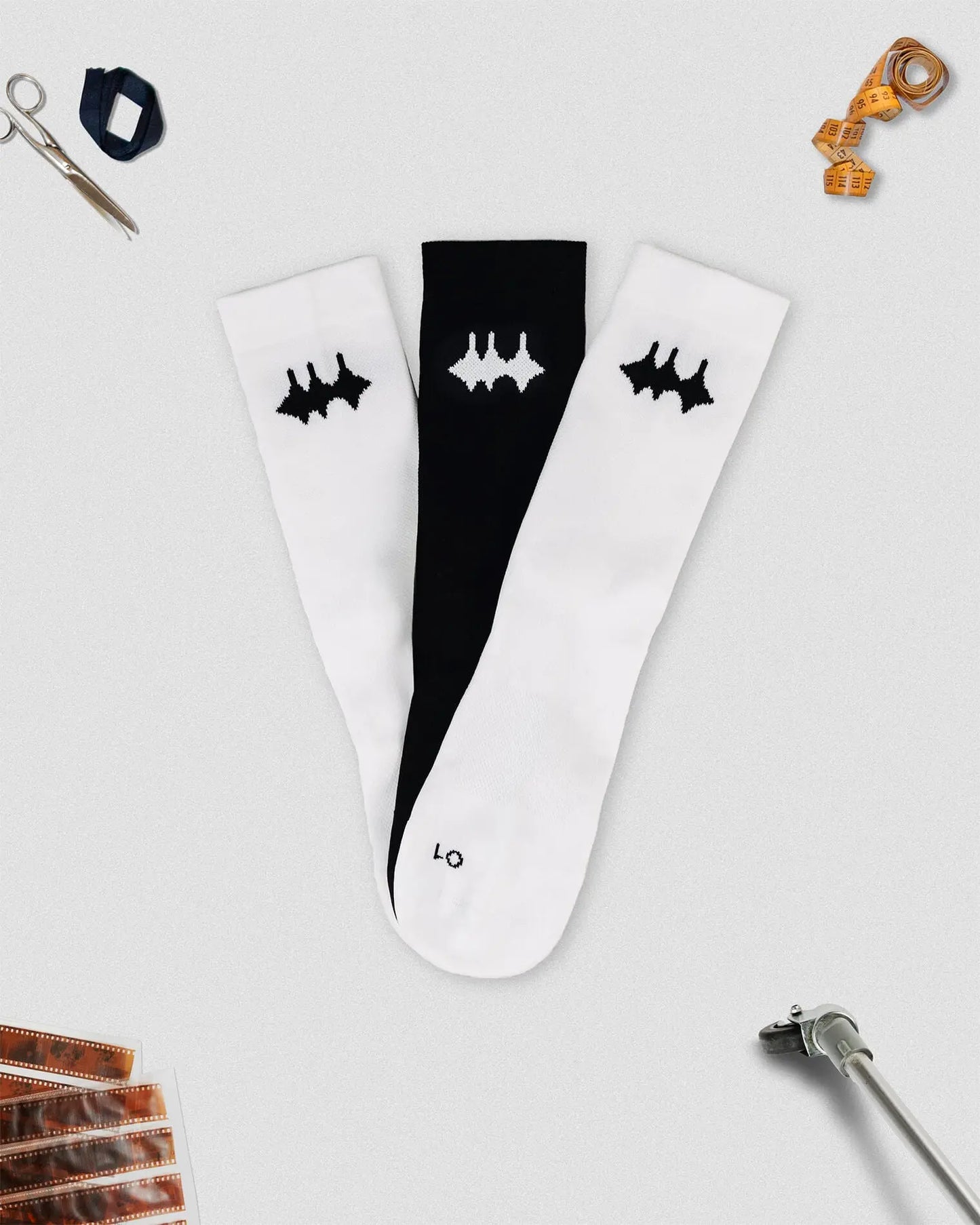 OG 01 mixed socks front flatlay with props — one black and one white sock forming contrast set with logo