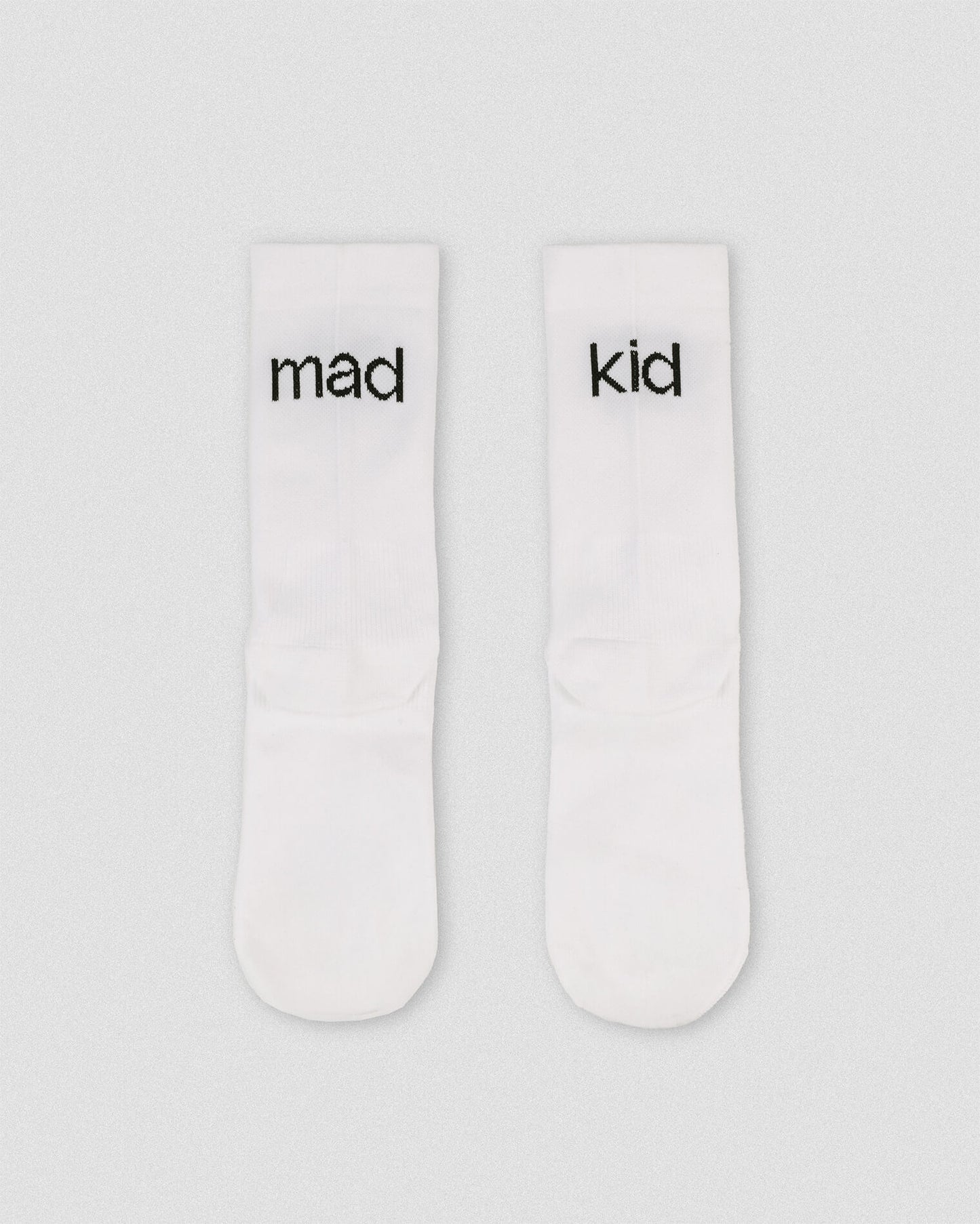 OG 01 white socks back flatlay — white athletic socks showing madkid lettering on back side
