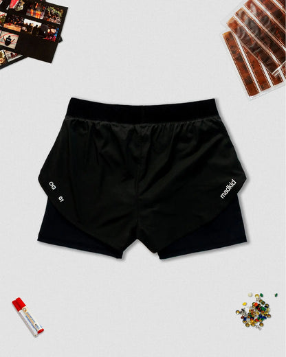 OG 01 women’s 2-in-1 shorts back flatlay — black performance shorts showing Madkid logo and OG 01 mark on lower hem