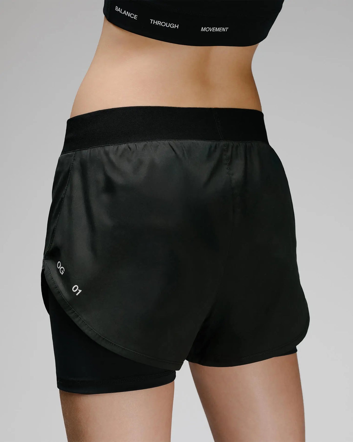 OG 01 women’s 2-in-1 shorts back on model — elastic waistband and OG 01 mark visible on back hem