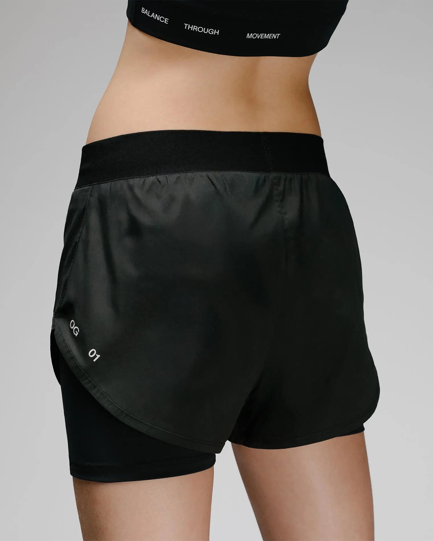 OG 01 women’s 2-in-1 shorts back on model — elastic waistband and OG 01 mark visible on back hem