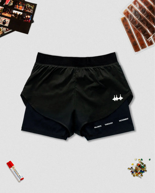 OG 01 women’s 2-in-1 shorts front flatlay — black double-layer running shorts with reflective Madkid logo and props on light background