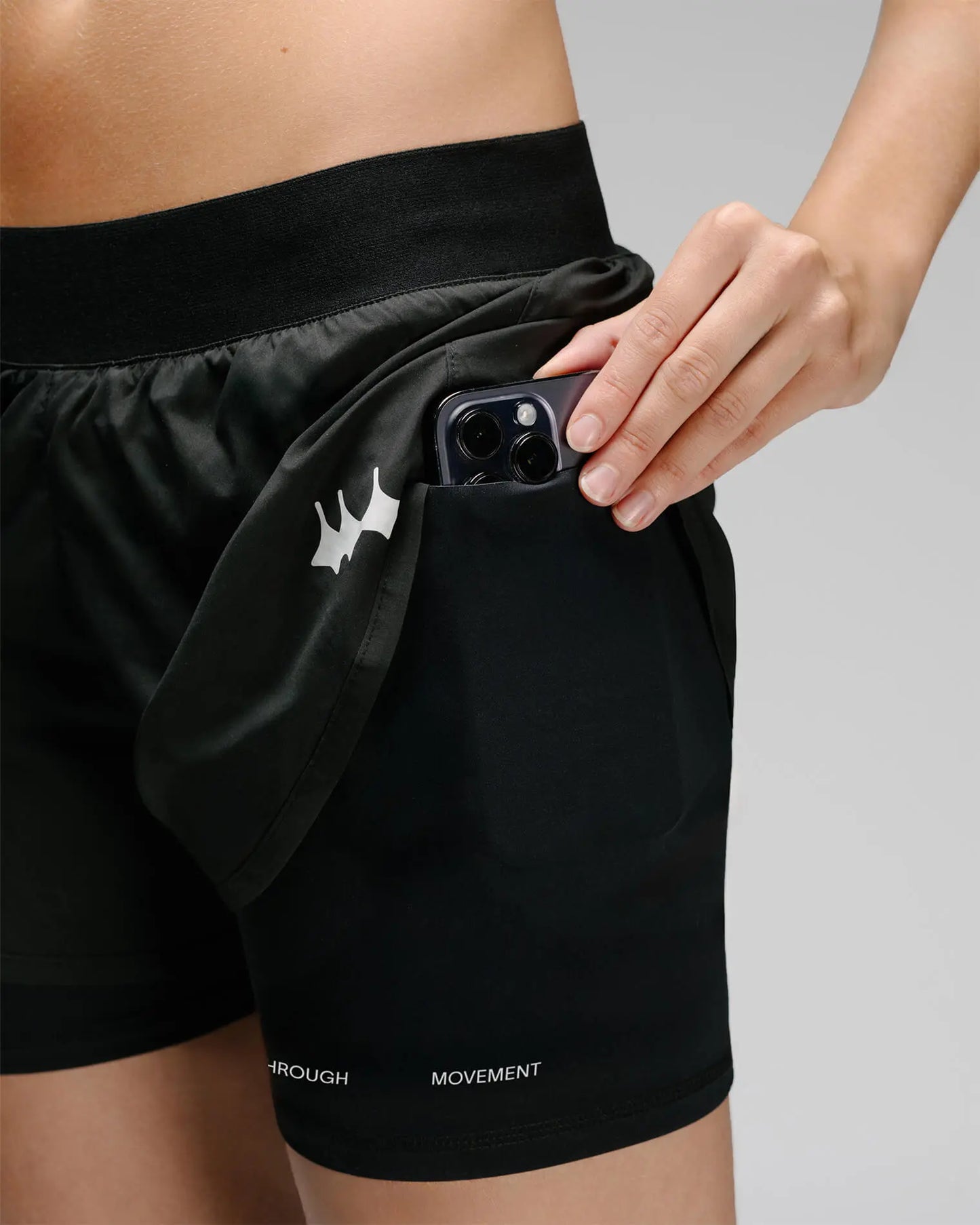 OG 01 women’s 2-in-1 shorts pocket feature on model — functional side pocket integrated into inner layer with reflective logo
