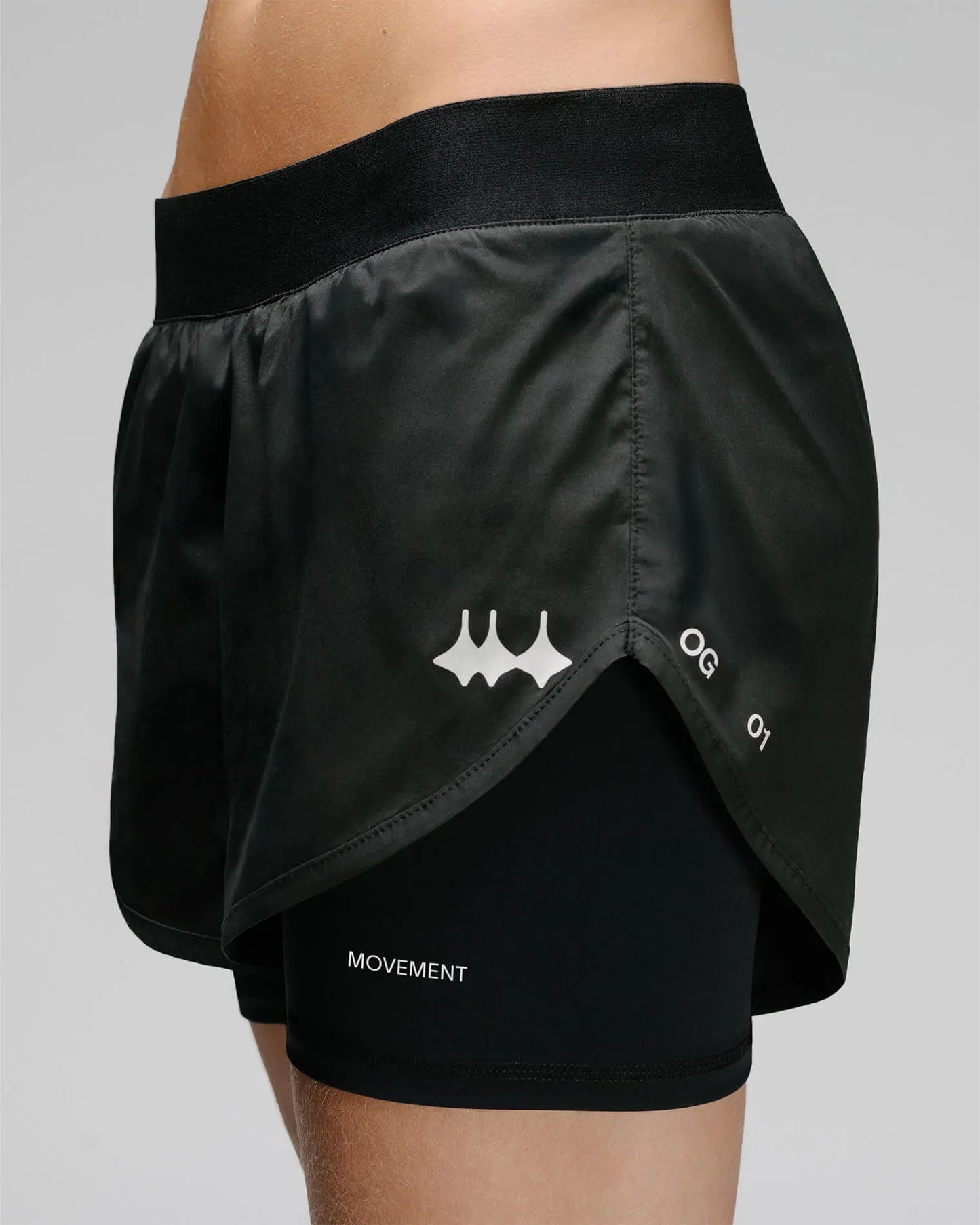 OG 01 women’s 2-in-1 shorts side detail on model — split hem revealing compression layer and printed logo