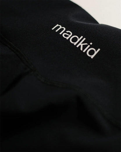 OG 01 women’s performance leggings logo detail — close-up of printed Madkid branding on black stretch fabric