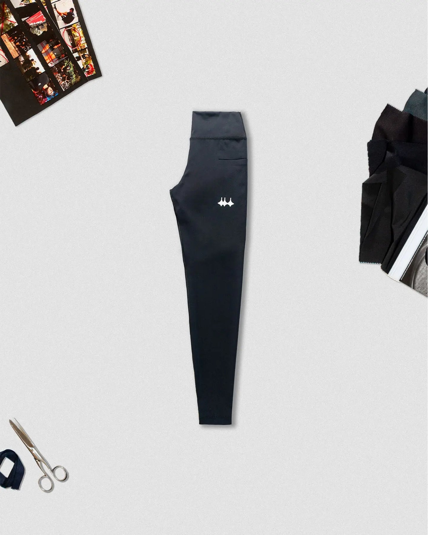 OG 01 women’s performance leggings side A flatlay — black technical leggings with logo and props on light background by Madkid