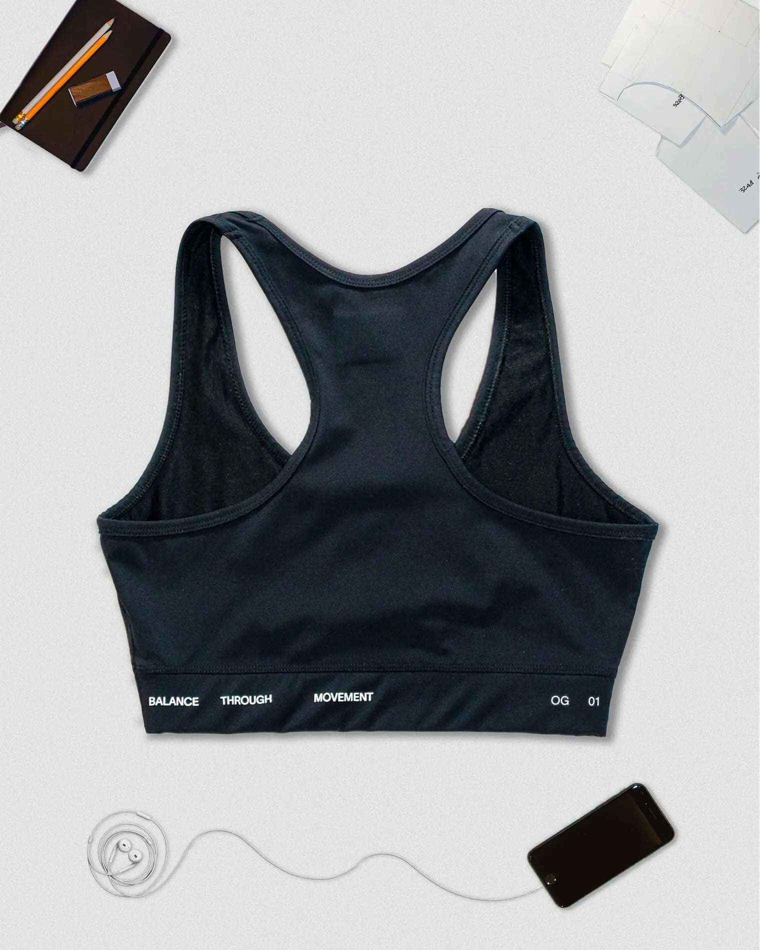 OG 01 women’s performance top back flatlay — racerback design showing Balance Through Movement slogan