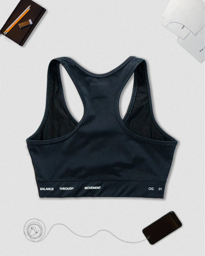 OG 01 women’s performance top back flatlay — racerback design showing Balance Through Movement slogan