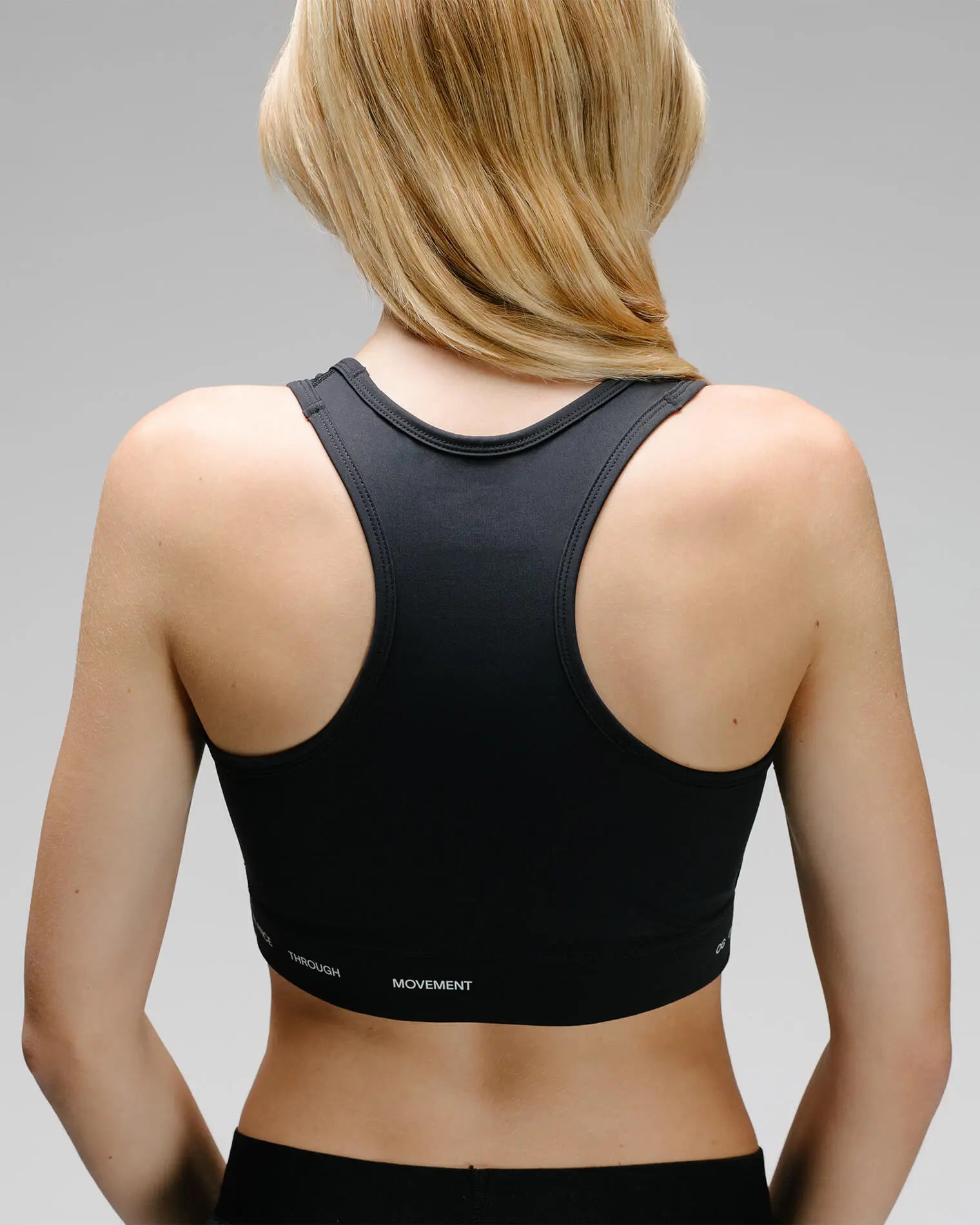 OG 01 women’s performance top back on model — racerback cut and elastic band showing Balance Through Movement text