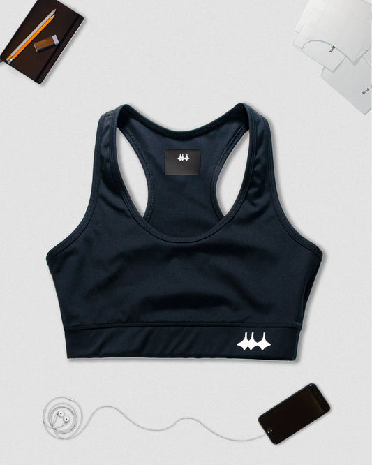 OG 01 women’s performance top front flatlay — black sports bra on light background with Madkid logo and accessories