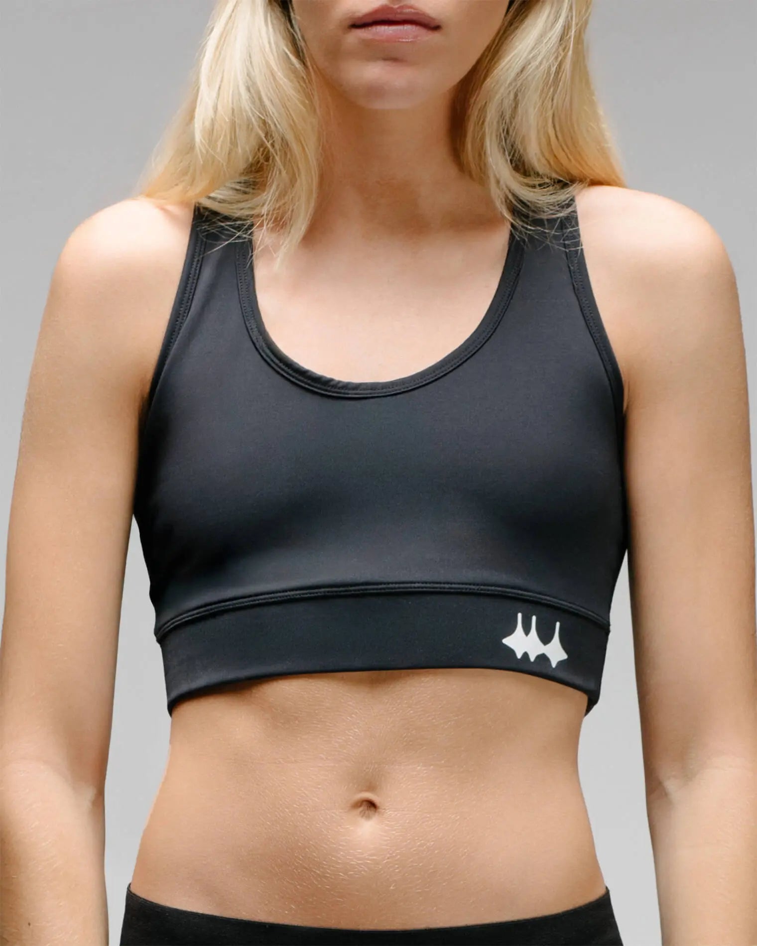 OG 01 women’s performance top front on model — close-up of fitted black sports bra with reflective Madkid logo