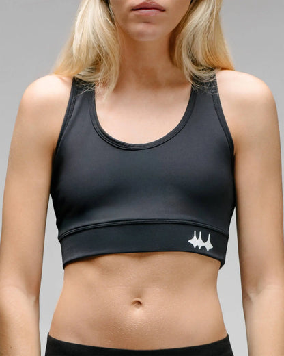 OG 01 women’s performance top front on model — close-up of fitted black sports bra with reflective Madkid logo